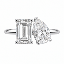 Load image into Gallery viewer, A silver engagement ring featuring a rectangular emerald-cut diamond on one side and a pear-cut diamond on the other, set on a polished silver band against a white background.