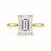 Load image into Gallery viewer, An emerald-cut diamond engagement ring with a yellow gold band and prongs, centered on a clean white background.

